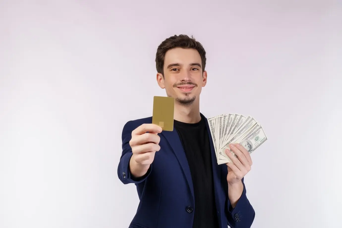 Portrait d’un jeune homme d’affaires beau et souriant montrant une carte de crédit et de l’argent liquide, isolé sur fond blanc.